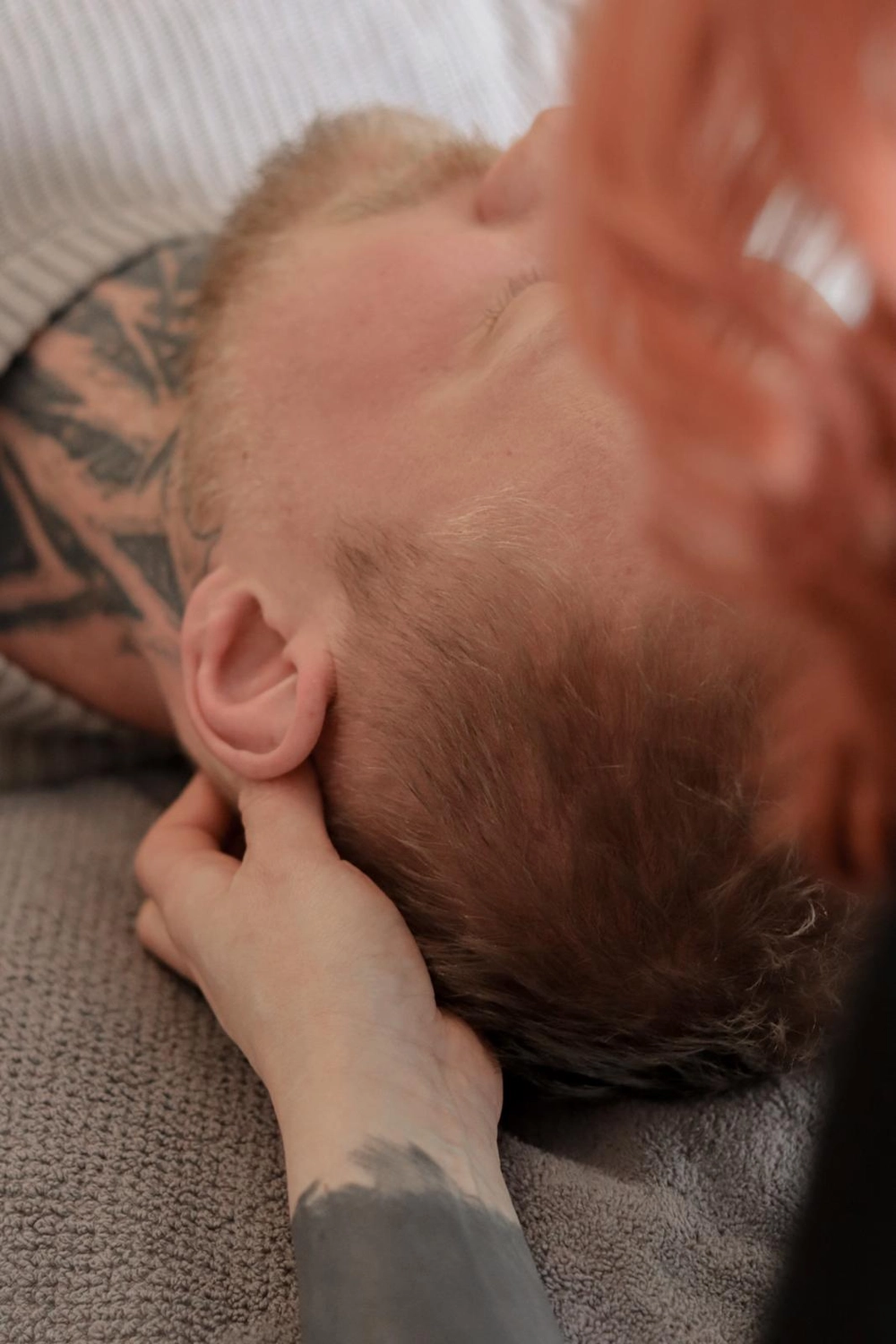 LPZ-Hübner - Physiotherapie und Lymphdrainage - Eine Nahaufnahme von hinten zeigt, wie der Kopf einer Person während einer therapeutischen Sitzung oder Massage von zwei Händen gehalten wird.